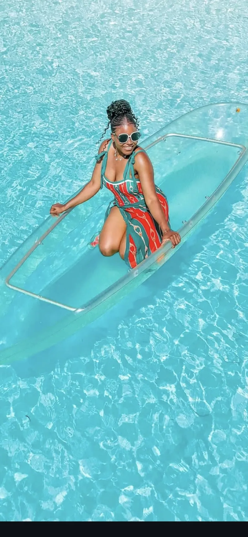 A woman kneeling in a glass-bottom kayak on Zanzibar's clear water
