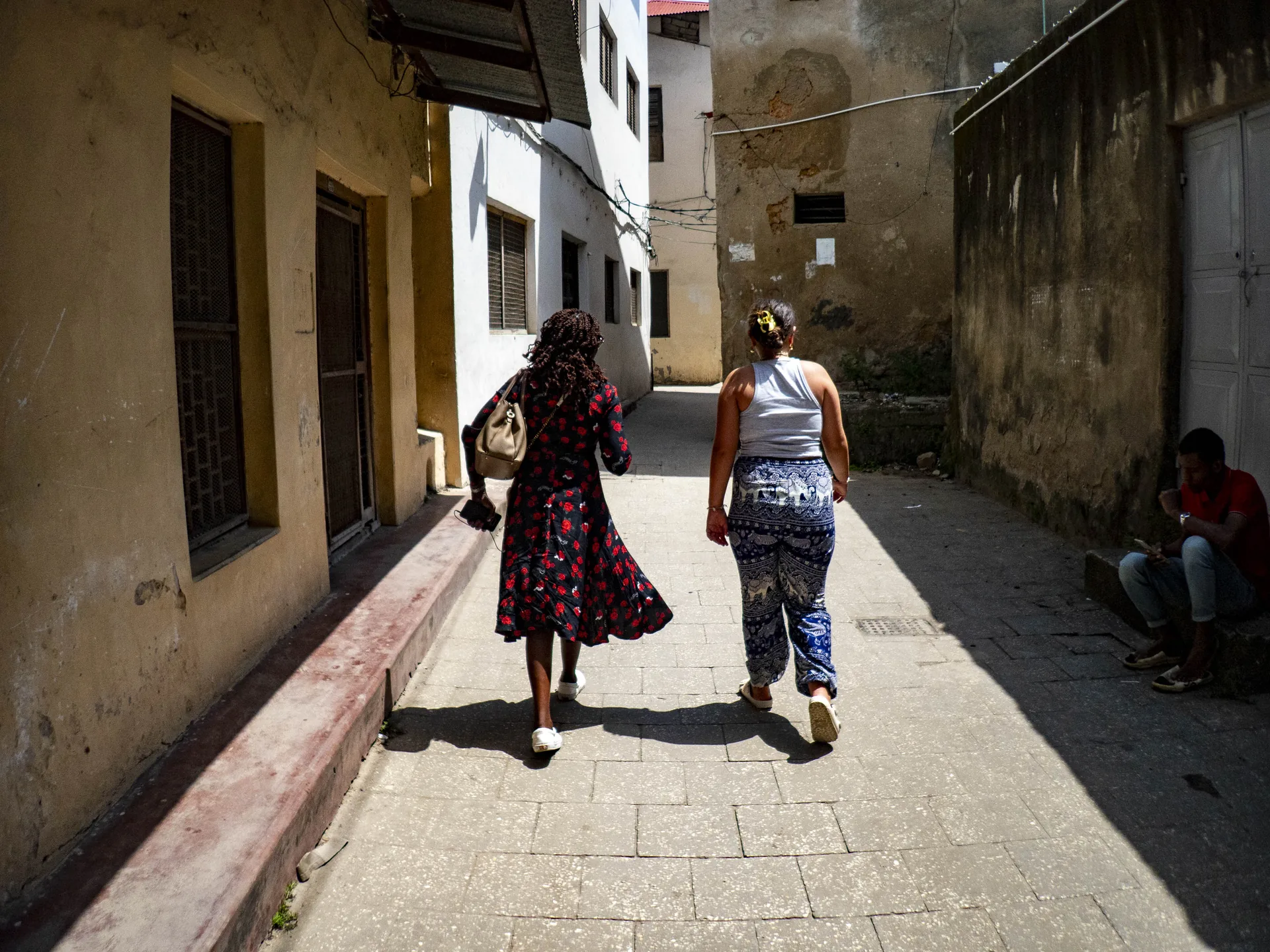 Two travellers walking a historic Stone Town alleyway in Zanzibar